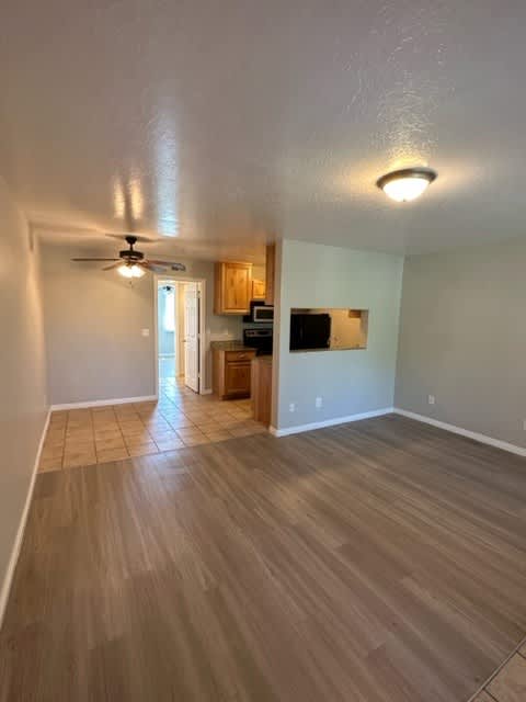 A room with a ceiling fan and wooden flooring.
