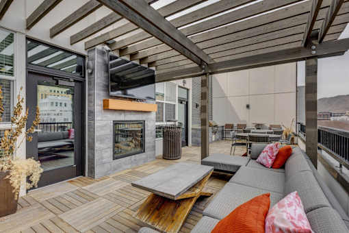 A modern outdoor patio with a fireplace and seating area.