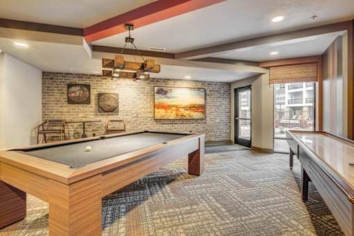 A room with a pool table and a brick wall.