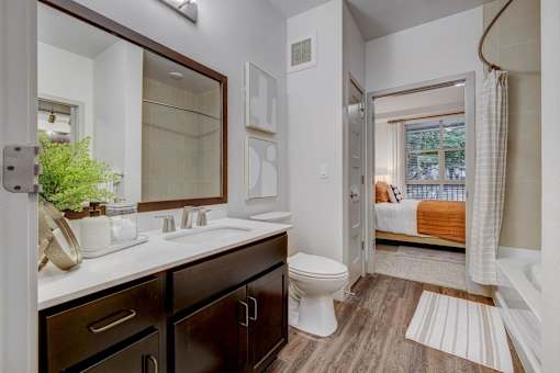 A bathroom with a toilet, sink, and mirror.