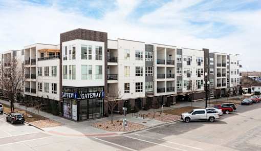A white car is parked in front of a building with a sign that says "Gateway Gateway.".