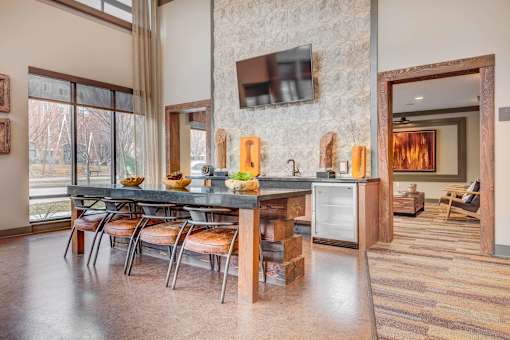 A kitchen with a table and chairs in front of a stone wall.
