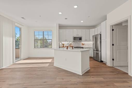 A modern kitchen with white cabinets and a wooden floor.