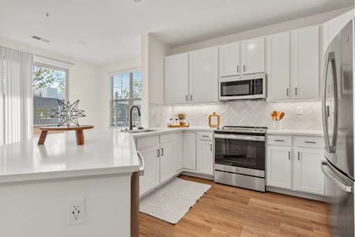 A modern kitchen with white cabinets and stainless steel appliances.