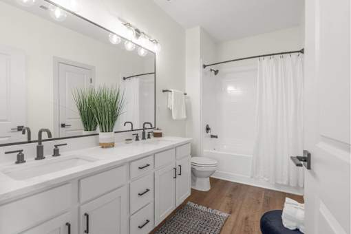 A white bathroom with a large mirror and lights above it.