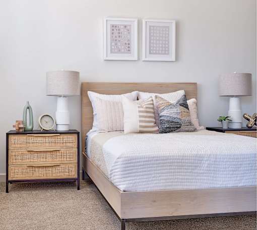 A bedroom with a bed, nightstand, and two framed pictures on the wall.