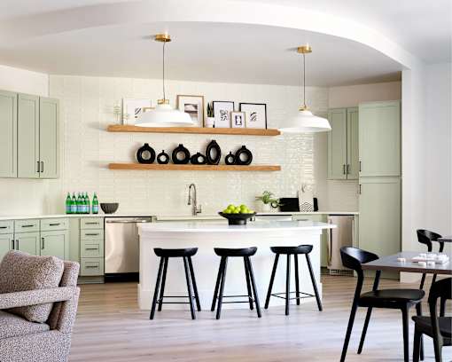 A kitchen with a white countertop and black bar stools.
