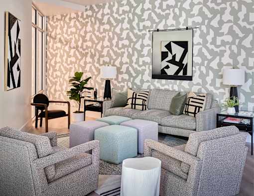 A living room with grey couches and a patterned wallpaper.
