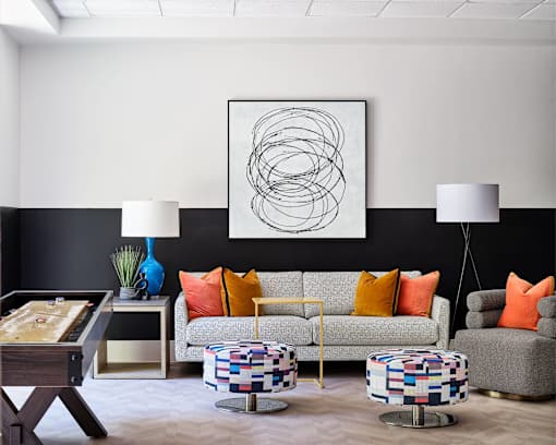 A modern living room with a pool table and a large abstract painting on the wall.