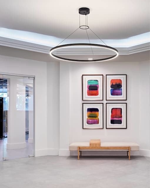 A white room with a bench and three framed pictures on the wall.