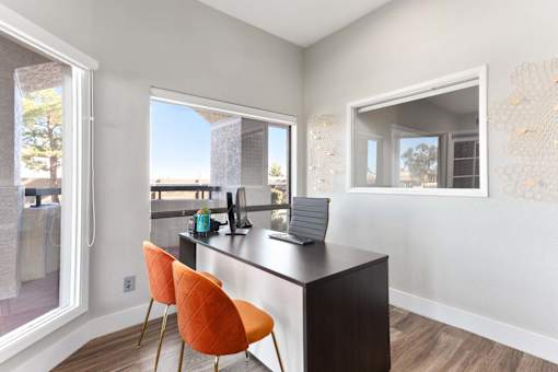 A kitchen with a black countertop and orange chairs.