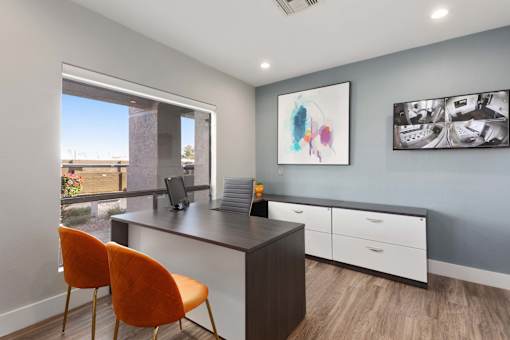 A room with a desk, chairs and pictures on the wall.