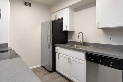 A small kitchen with a black refrigerator and white cabinets.