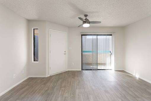 A room with a ceiling fan and a sliding glass door leading to a balcony.