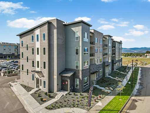 A modern apartment building with a parking lot in front.