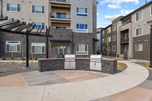 A modern outdoor kitchen area with a grill and sink.