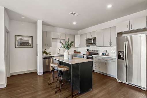A modern kitchen with a black island and stainless steel appliances.