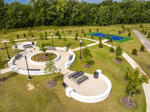 A park with a circular white structure and a blue pool in the background.