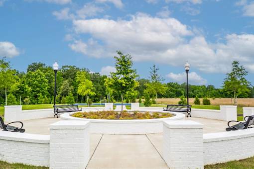 A park with a white brick wall and benches.