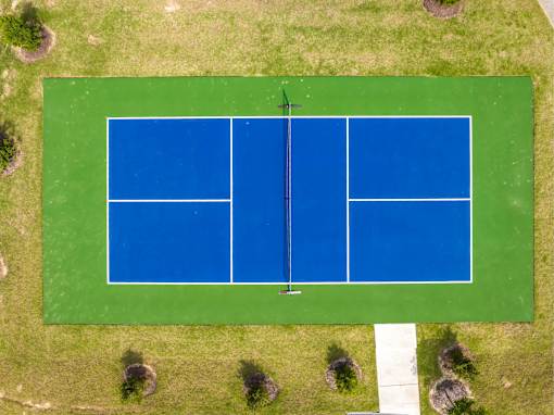 A tennis court surrounded by grass and trees.