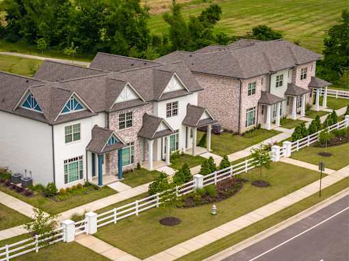 A white house with a grey roof and a white fence.