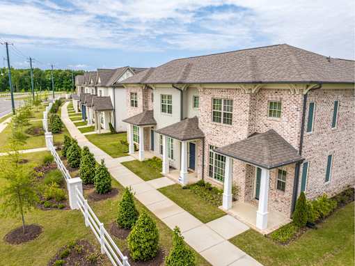 A row of houses with white picket fences and green lawns.