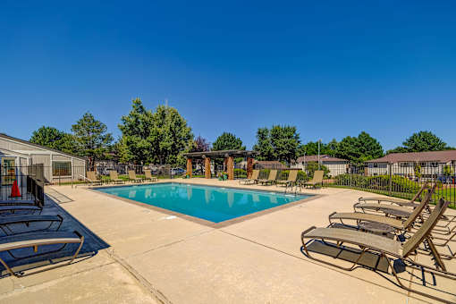 A large swimming pool surrounded by lounge chairs and trees.