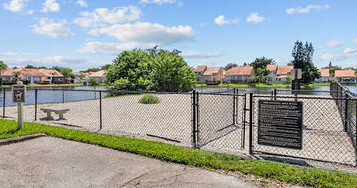 A fenced area with a signboard and a tree in the background.