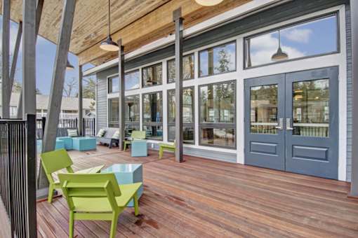 A wooden deck with green chairs and a blue table.