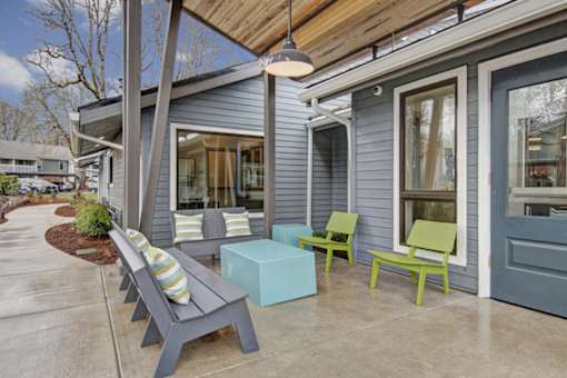 A grey house with a blue door and a green chair.