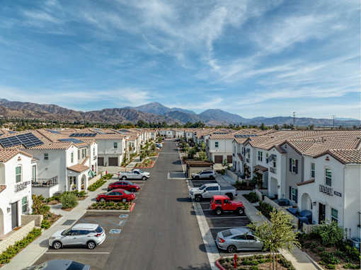 A row of houses with cars parked in front of them.