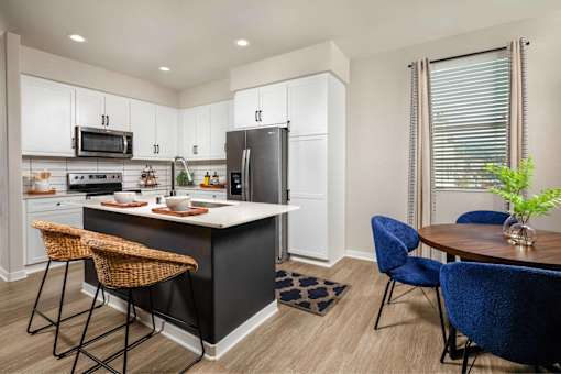 A kitchen with a black island and blue chairs.
