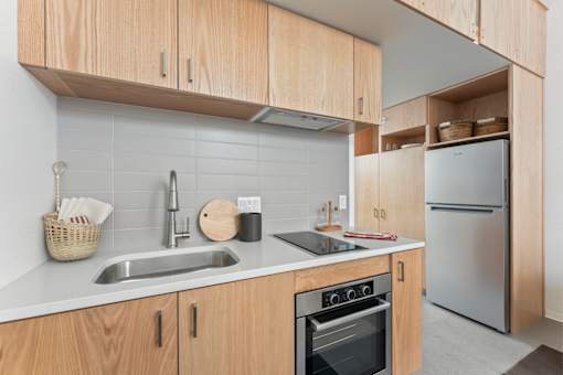 A kitchen with wooden cabinets and a stainless steel refrigerator.