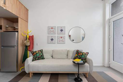 A living room with a couch, a mirror, and pictures on the wall.