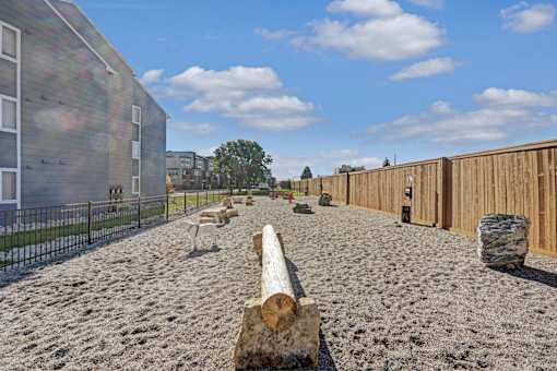 A sandy area with a log and a fence in the background.