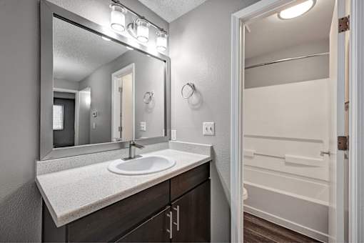 A bathroom with a sink, mirror, and towel rack.