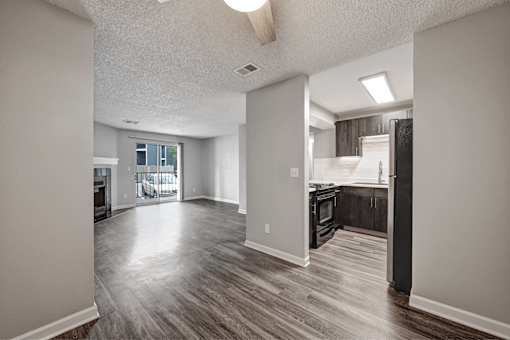 A spacious living room with a kitchen in the background.