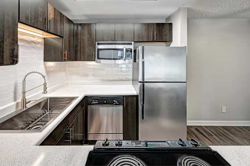 A modern kitchen with a stainless steel refrigerator and a black stove top.