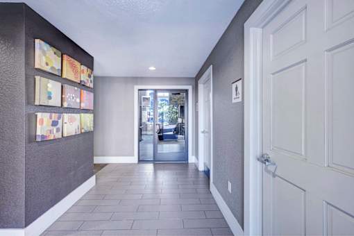 A hallway with a wall of pictures and a door on the right.