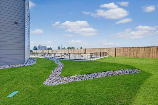 A backyard with a stone pathway and a wooden fence.
