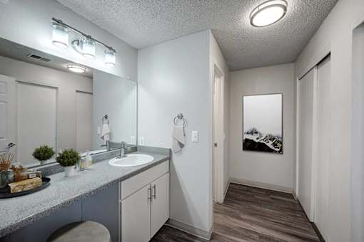 A bathroom with a grey counter top and a grey and white cabinet.