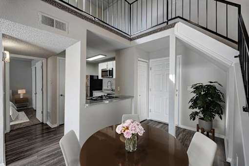 A dining room with a table and chairs and a potted plant.