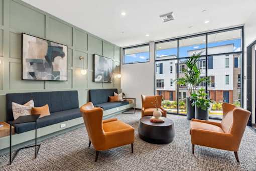 A modern living room with a grey sofa, orange chairs, and a coffee table.