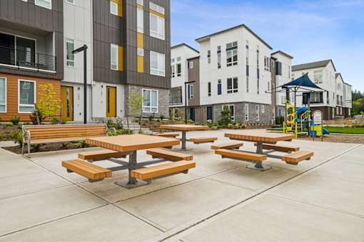 Picnic tables are set up in a courtyard between two buildings.