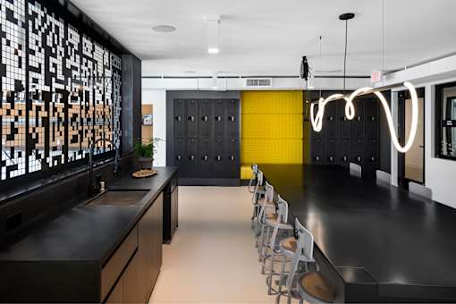 A modern kitchen with a black countertop and yellow accent wall.