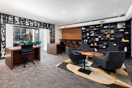 A modern office space with a black and white patterned curtain, a bookshelf, and a grey carpet