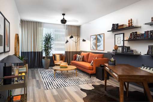A living room with a black and white striped rug, a brown leather couch, and a wooden coffee table