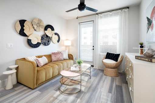 A living room with a beige sofa, a round coffee table, and a wall decorated with circular plates.