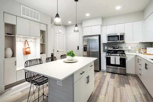 A modern kitchen with a white island and stainless steel appliances.