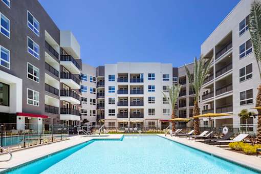 A large swimming pool is surrounded by apartment buildings.